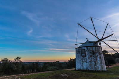 Traditional windmill on field against sky at sunset