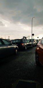 Vehicles on road against cloudy sky