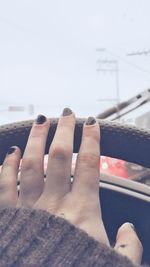 Close-up of hands against sky