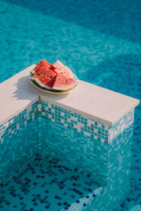 Close-up of watermelon in plate by swimming pool