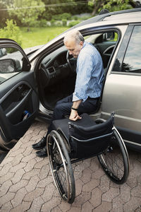 Disabled man disembarking from car on wheelchair