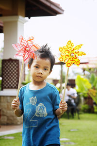 Boy standing with pinwheel toys on field in yard