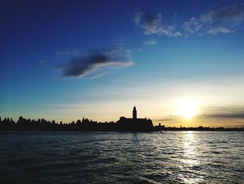 Silhouette of lighthouse in city at sunset