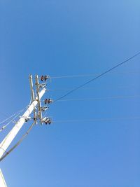 Low angle view of power lines against clear blue sky