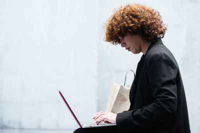 Side view of man using laptop while sitting on table