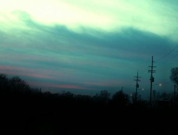 Low angle view of power lines against cloudy sky