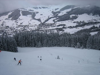 People skiing on snow against mountains