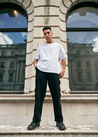 Full length portrait of young man standing against built structure