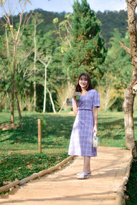 Full length of young woman standing against trees