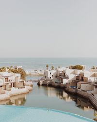 High angle view of river amidst buildings by sea against clear sky