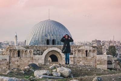 Rear view of man standing by buildings against sky