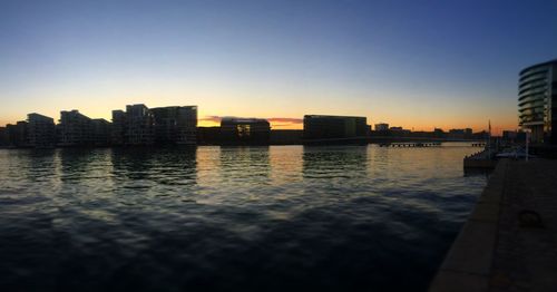 Reflection of buildings in calm river at sunset