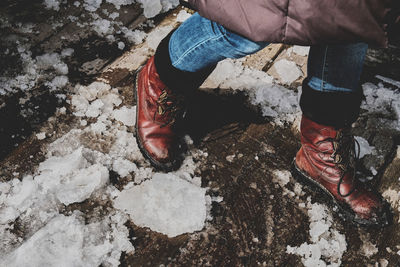 Low section of man walking on footpath with snow