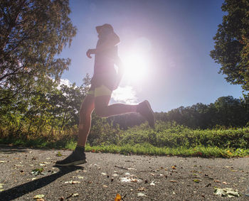 Slim body guy runs on path with fallen leaves. warm day for outdoor excersising.