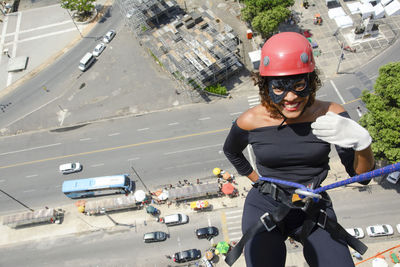 A woman wearing a hero costume with protective helmet walking down a tall rappel building. 