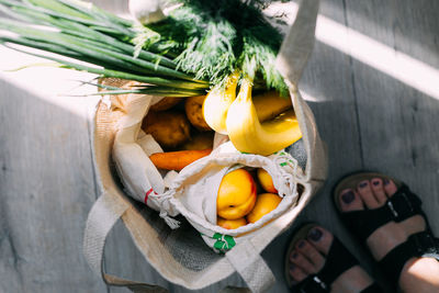 Low section of woman standing on wooden floor with food