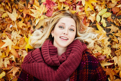 Portrait of young woman lying on autumn leaves