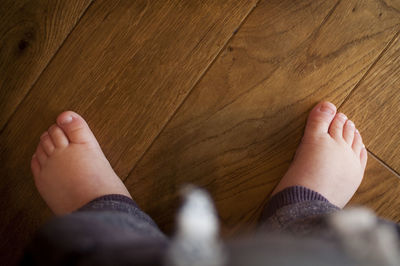 Low section of baby standing on hardwood floor