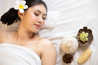 High angle view of woman wearing towel relaxing on bed in spa