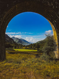 Scenic view of field and mountains against blue sky