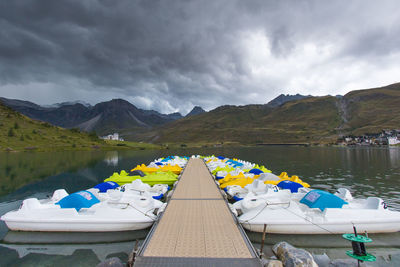 Tignes lake with pedal boat at the foot of the haute tarentaise mountains under a stormy sky