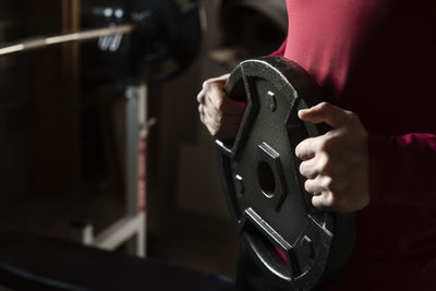 Midsection of man holding barbell at gym