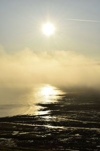 Sun shining through clouds over sea