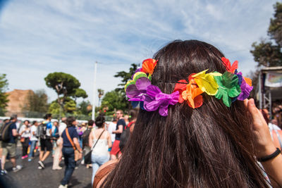 Rear view of woman with multi colored flowers against sky