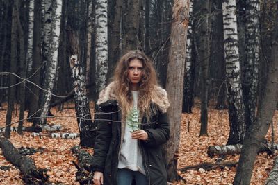 Portrait of woman standing in forest during winter