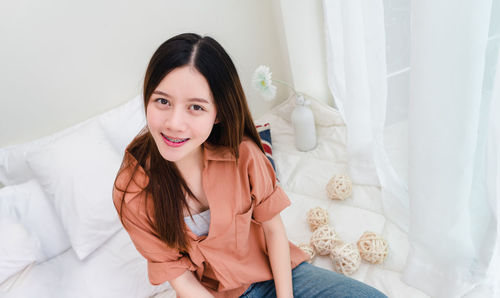 Portrait of smiling young woman sitting on bed
