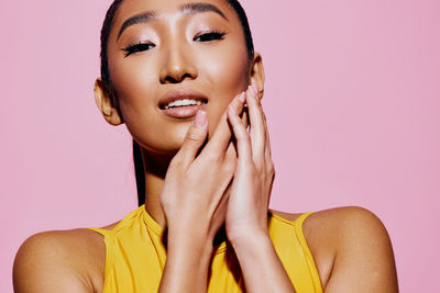 Close-up of young woman against pink background