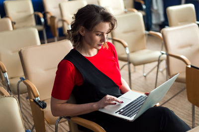 Young business woman or manager sitting at conference hall with laptop