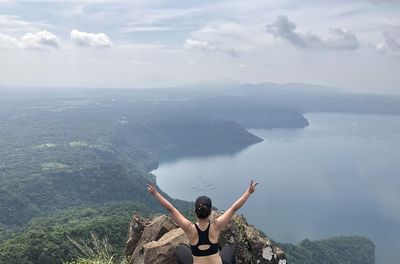 Rear view of person with arms raised against sky