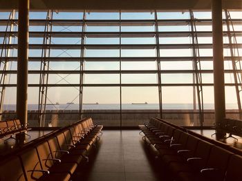 Empty chairs against sky seen through glass window