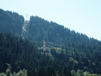 Overhead cable car in forest against clear sky