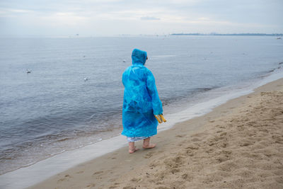 Woman in raincoat walking at beach