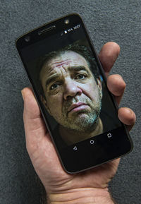 Cropped hand of man holding mobile phone with photograph