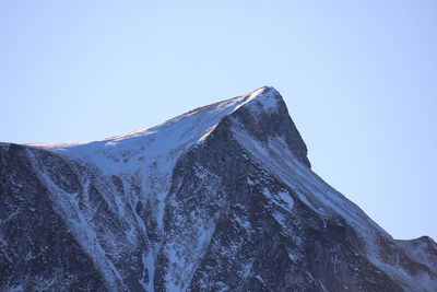 Low angle view of snowcapped mountain against clear blue sky