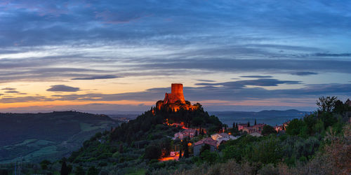 Lighthouse on mountain against sky during sunset