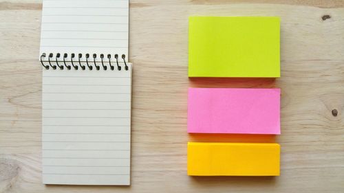 Directly above shot of multi colored adhesive notes and book on table