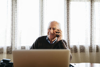 Portrait of smiling senior man on the phone at home