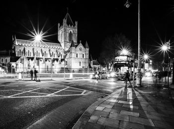 People on illuminated street amidst buildings at night