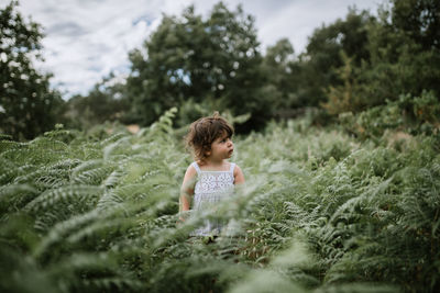 Cute girl looking away standing in plants