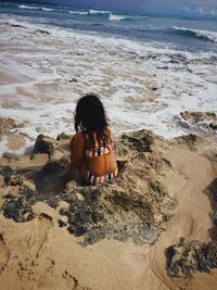 Rear view of girl sitting at beach