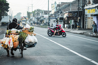 Rear view of people riding motorcycle on road