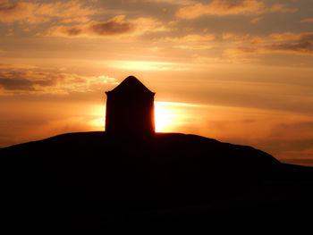 Silhouette house against orange sky