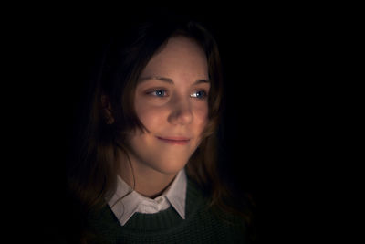 Close-up portrait of smiling woman against black background