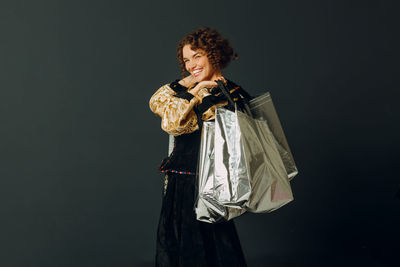 Portrait of woman standing against black background