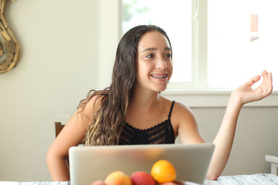 Portrait of smiling young woman using mobile phone at home