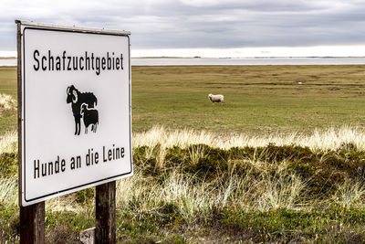 Information sign on field against sky